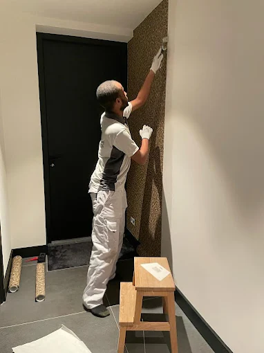 Behanger brengt behang aan in hal